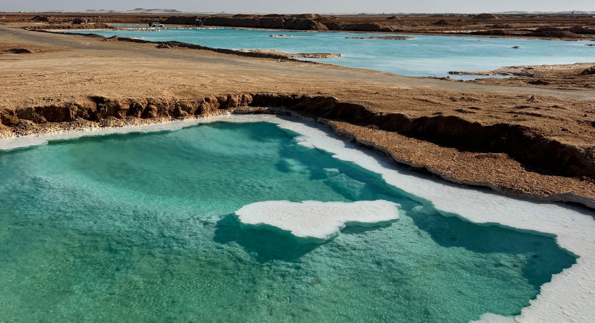 Turquoise salt pools ringed with white salt in the Siwa desert