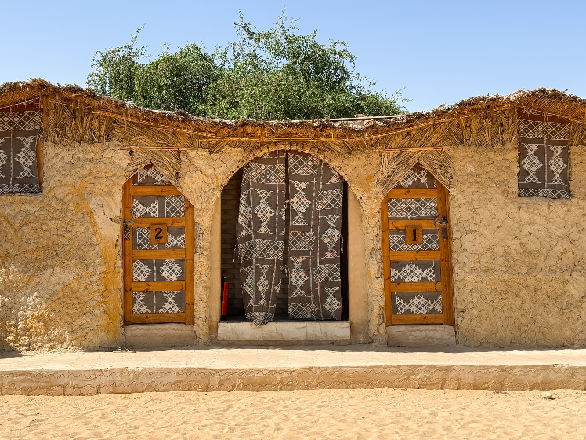 Traditional mud-brick guest rooms with woven doors in Siwa